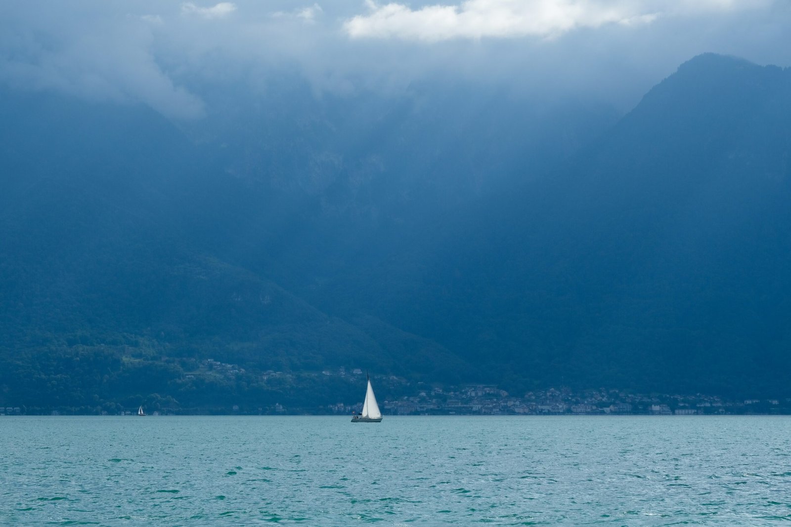 a sailboat in a large body of water with mountains in the background